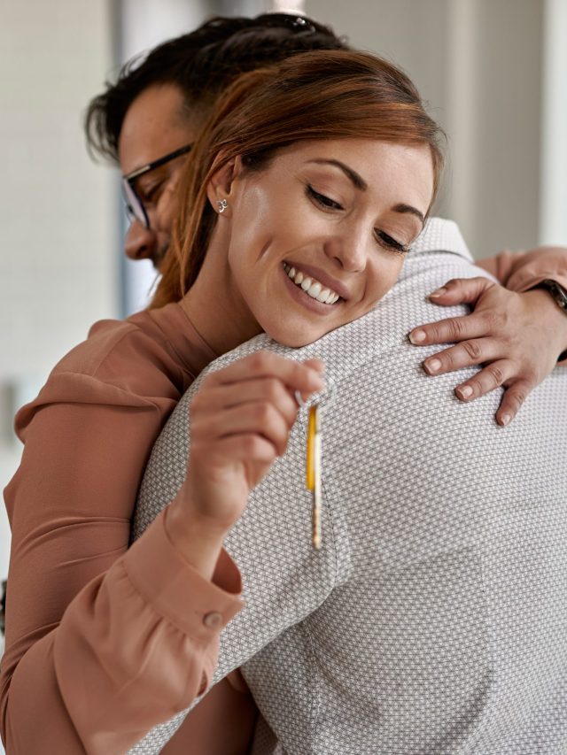 young-happy-couple-embracing-while-buying-their-first-home-focus-is-on-woman-holding-new-house-keys